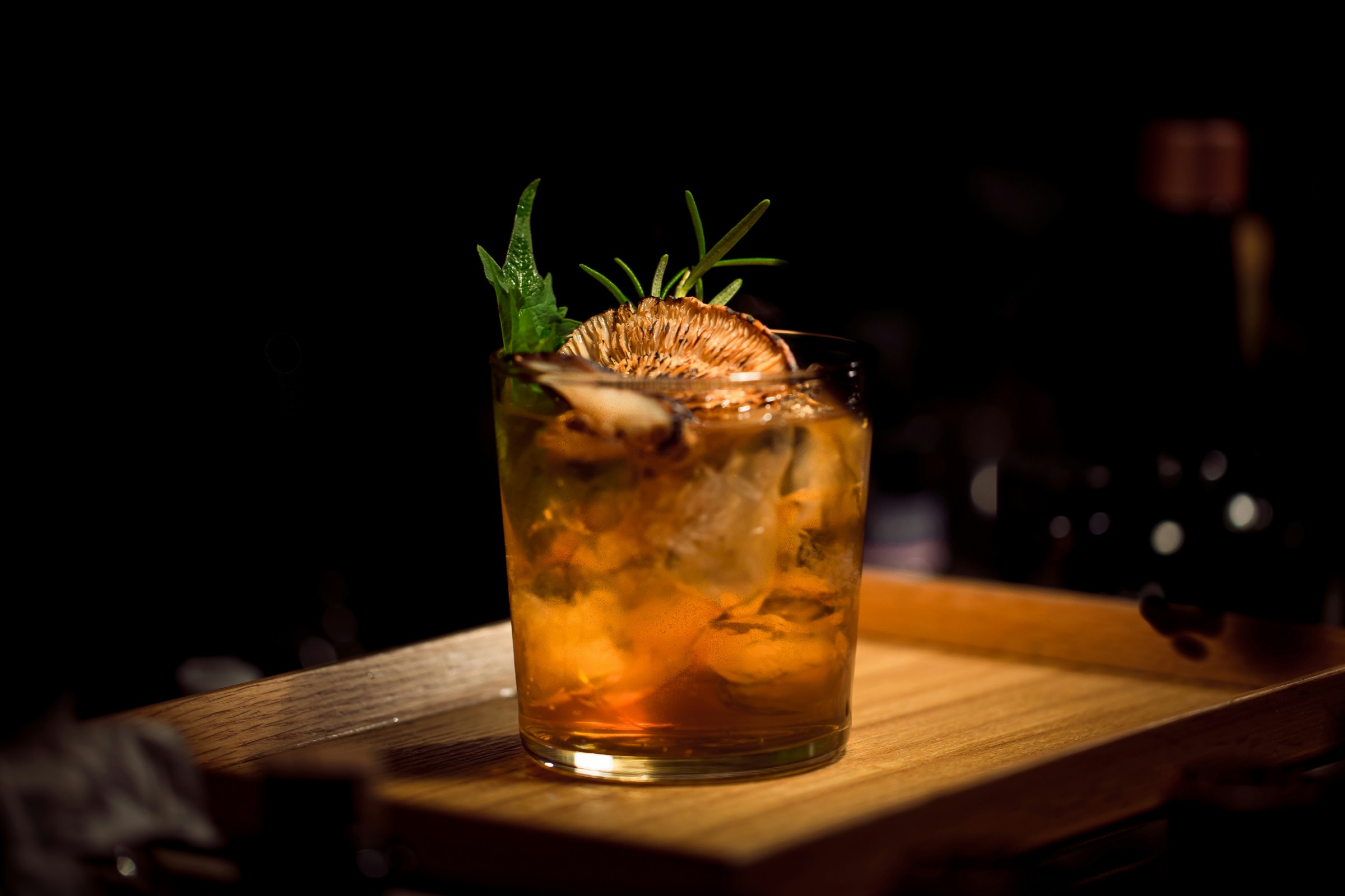 An amber cocktail with a dried citrus garnish